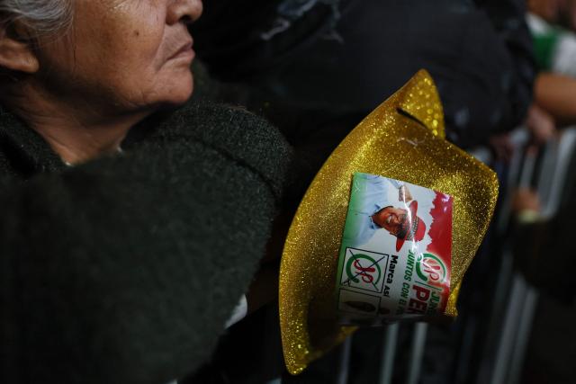 A supporter holds a hat with a portrait of Peru's presidential candidate for the Juntos por el Peru party, Roberto Sanchez, during his closing campaign rally in Lima on June 4, 2026. Right-wing candidate Keiko Fujimori and leftist Roberto Sanchez will face off in Peru's presidential runoff on June 7, 2026. (Photo by Connie FRANCE / AFP)