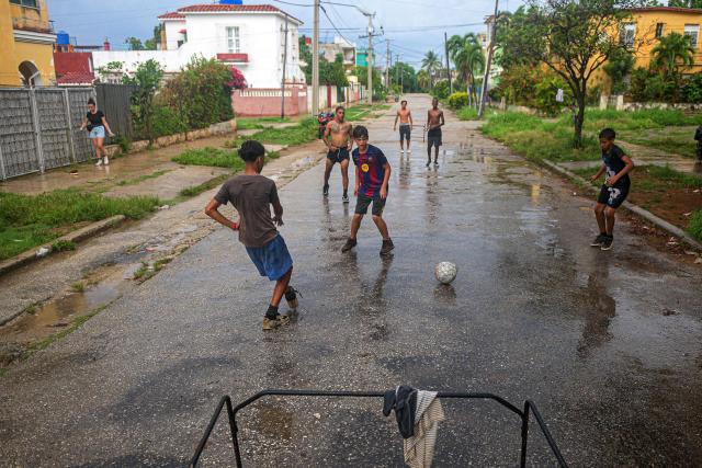 Teenagers play football on a wet street in Havana on June 4, 2026. (Photo by AFP)