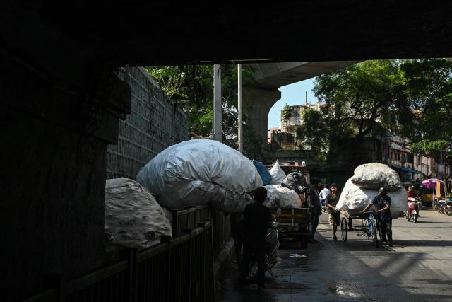 Workers dump sacks of plastic wastes on a roadside in Hyderabad on June 5, 2026. (Photo by Noah SEELAM / AFP)
