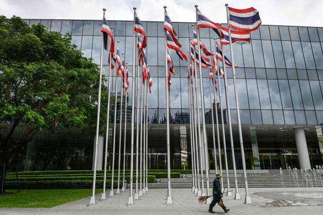 A worker walks past Thai national flags displayed outside the Queen Sirikit National Convention Center in Bangkok on June 4, 2026. (Photo by Amaury PAUL / AFP)