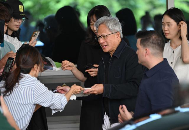 Nvidia CEO Jensen Huang gives his autographs to fans as he arrives at Gimpo airport in Seoul on June 5, 2026. (Photo by Jung Yeon-je / AFP)