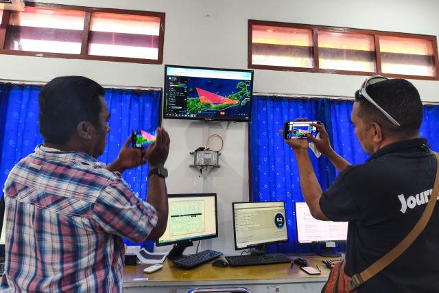 Journalists photograph a screen showing the movement of volcanic ash from Mount Lewotobi Laki-laki at the Meteorology, Climatology and Geophysics Agency (BMKG) office in Maumere, East Nusa Tenggara, Indonesia, on June 5, 2026. A highly active volcano in eastern Indonesia erupted several times on June 5, spewing towering ash columns into the sky and forcing a local airport to close, authorities said. Mount Lewotobi Laki-Laki on Flores Island erupted at 11:15 am (0315 GMT), sending volcanic material 2.5 kilometres (1.6 miles) into the air, the national volcanology agency said in a statement. (Photo by Arnold Welianto / AFP)