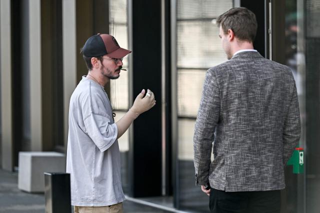 Injured fire survivor Flavio Ricchitelli smokes a cigarette prior to a hearing of the owners of Le Constellation in Crans-Montana, as part of the inquiry into a devastating New Year's fire, in Sion on June 5, 2026. The French couple Jacques and Jessica Moretti were to be cross-examined by public prosecutors and lawyers for civil parties caught up in the blaze that engulfed Le Constellation bar in Crans-Montana in the early hours of January 1, 2026. The tragedy killed 41 people, mostly teenagers, and injured 115 others. (Photo by Fabrice COFFRINI / AFP)
