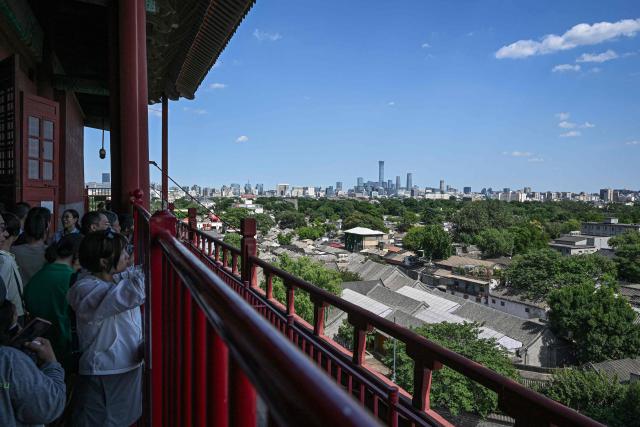 People enjoy the view of the city's skyline and traditional Hutong alleyway houses from the Drum Tower in Beijing on June 5, 2026. (Photo by Jade GAO / AFP)