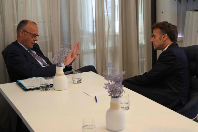 German Chancellor Friedrich Merz (L) and French President Emmanuel Macron speak with each other ahead of a meeting on the sidelines of the EU-Western Balkans Summit at Porto Montenegro in Tivat on June 5, 2026. (Photo by Ludovic MARIN / AFP)