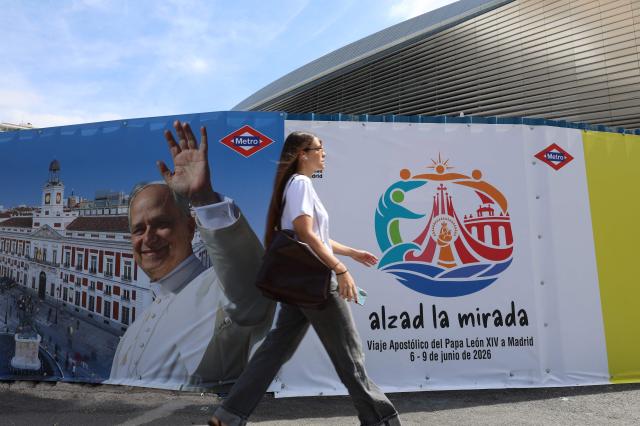 A woman walks past advertisements of Pope Leo XIV's upcoming trip to Madrid, part of a six day trip to Spain, next to the Santiago Bernabeu stadium Madrid on June 6, 2026. Pope Leo XIV is scheduled to begin a seven-day Apostolic trip to Spain on June 6, including stops in Madrid where he will hold a mass in Cibeles Square, Barcelona where he is to hold a mass in the iconic Sagrada Familia cathedral and inaugurate the tower of Jesus Christ, and the Canary Islands where he will meet with migrants and organisations dedicated to helping them. (Photo by Pierre-Philippe MARCOU / AFP)