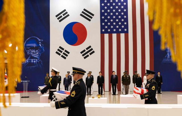 South Korean and US honour guards carry coffins containing the remains of soldiers killed in the 1950-53 Korean War during a repatriation ceremony at Seoul Military Air Base in Seongnam on June 5, 2026.  (Photo by JEON HEON-KYUN / POOL / AFP)