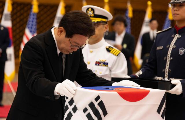 South Korea's President Lee Jae Myung pays tribute to soldiers killed in the 1950-53 Korean War during a repatriation ceremony at Seoul Military Air Base in Seongnam on June 5, 2026.  (Photo by JEON HEON-KYUN / POOL / AFP)