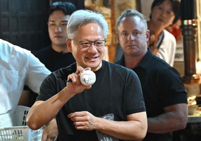 Nvidia CEO Jensen Huang holds his signed baseball during the dinner with SK Group Chairman Chey Tae-won, LG Group Chairman Koo Kwang-mo and Naver founder and Chairman Lee Hae-jin at a Korean barbecue restaurant in Seoul on June 5, 2026. Nvidia chief executive Jensen Huang arrived in Seoul on June 5, for a packed schedule of meetings with tech leaders, promising "some surprises" for South Korea while predicting robotics will be the country's next major growth sector. (Photo by Jung Yeon-je / AFP)