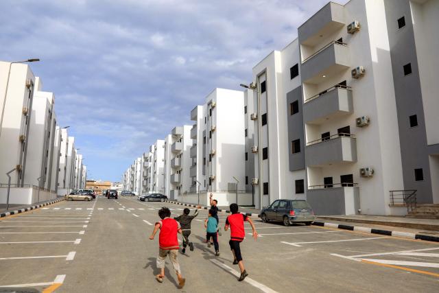 Children run along a street past new housing projects in Libya's eastern city of Derna on May 15, 2026. Nearly three years after a catastrophic storm tore through eastern Libya's port city of Derna killing almost 4,000 people the city is getting back on its feet, although the trauma persists. New roads and bridges, thousands of new homes, and a hospital have risen from the rubble since a storm swept the coastal city in 2023, leaving thousands missing and over 40,000 homeless. (Photo by Abdullah DOMA / AFP)