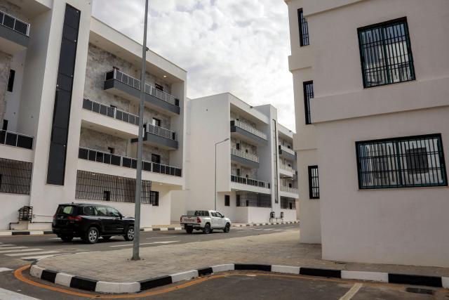 Vehicles move along a street past new housing projects in Libya's eastern city of Derna on May 15, 2026. Nearly three years after a catastrophic storm tore through eastern Libya's port city of Derna killing almost 4,000 people the city is getting back on its feet, although the trauma persists. New roads and bridges, thousands of new homes, and a hospital have risen from the rubble since a storm swept the coastal city in 2023, leaving thousands missing and over 40,000 homeless. (Photo by Abdullah DOMA / AFP)