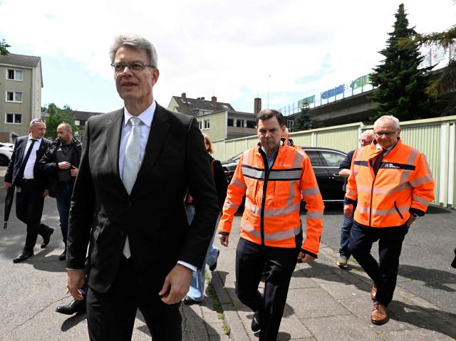 German Transport Minister Patrick Schnieder (L) is followed by employees of Germany's highway operator Die Autobahn GmbH as he arrives to visit the dilapidated Nord-Bruecke bridge crossing the Rhine in Bonn, western Germany, on June 5, 2026, after the bridge had to be closed due to severe damage. (Photo by Roberto Pfeil / AFP)