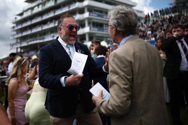 A racegoer celebrates on the opening day of the Epsom Derby Festival horse racing event in Surrey, southern England on June 5, 2026. (Photo by Henry Nicholls / AFP)