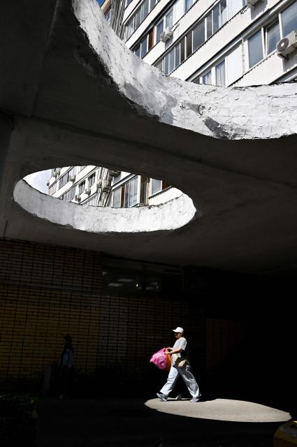 A woman walks under the canopy of a block apartment residential building in Moscow on June 5, 2026. (Photo by Alexander NEMENOV / AFP)