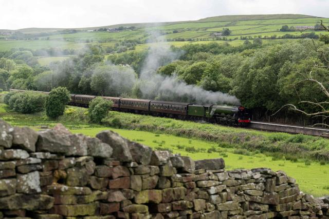 The Flying Scotsman steam locomotive travels along the East Lancashire Railway's line approaching Irwell Vale Station, near Bury in northern England on June 5, 2026. The Flying Scotsman was built in 1923 and holds the record for becoming the first steam locomotive to be officially authenticated at reaching 100 miles per hour on November 30, 1934. Following a 4.2 million GBP refurbishment, the Flying Scotsman returned to the UK's mainline in 2016. The East Lancashire Railway runs a 12 mile heritage railway line between the stations of Heywood and Rawtenstall. (Photo by Oli SCARFF / AFP)