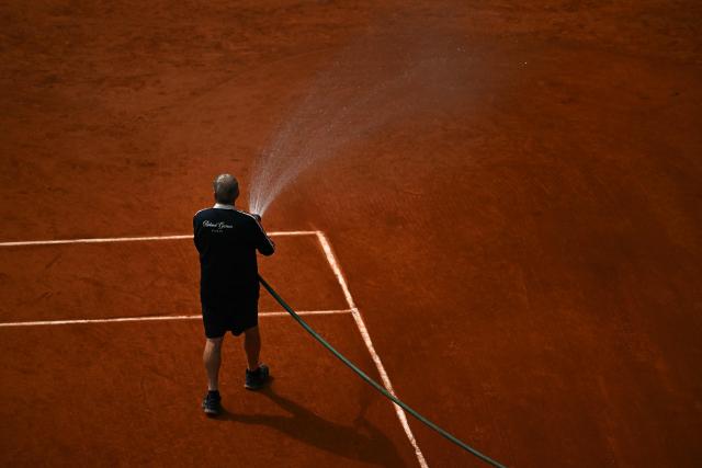 A Ground Staff water the clay during the men's semi final singles match between Czech Republic's Jakub Mensik and Germany's Alexander Zverev on day 13 of the French Open tennis tournament on Court Philippe-Chatrier at the Roland-Garros Complex in Paris on June 5, 2026. (Photo by JULIEN DE ROSA / AFP)