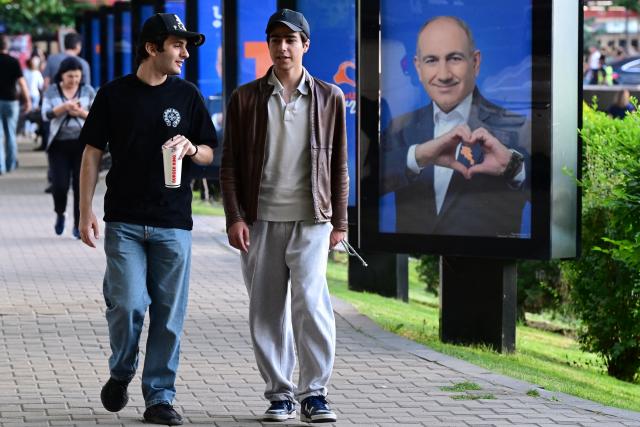 People walk past campaign posters of Armenian Prime Minister Nikol Pashinyan's Civil Contract party in Yerevan on June 5, 2026, days ahead of the parliamentary elections. (Photo by Karen MINASYAN / AFP)