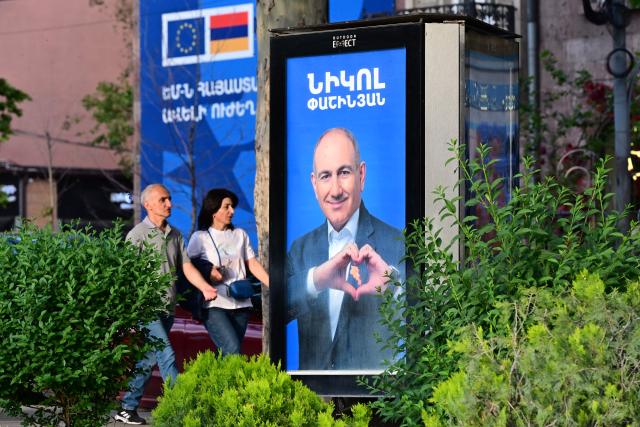 People walk past campaign posters of Armenian Prime Minister Nikol Pashinyan's Civil Contract party in Yerevan on June 5, 2026, days ahead of the parliamentary elections. (Photo by Karen MINASYAN / AFP)
