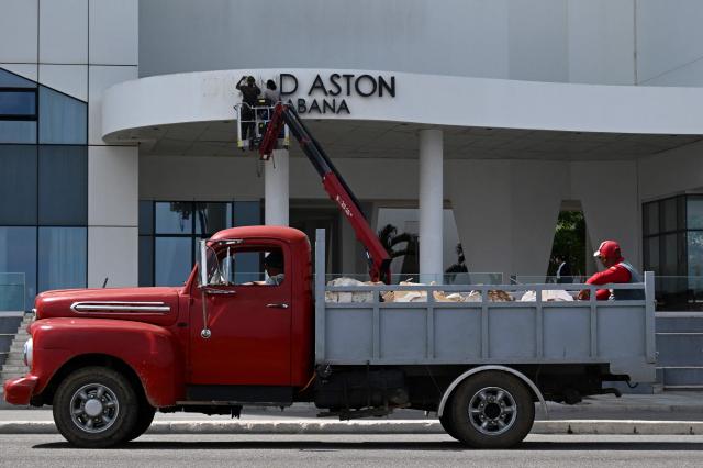 Maintenance workers remove the sign from the Hotel Grand Aston in Havana on June 5, 2026. The Asian group Archipelago International, which came to operate six hotels on the island under the Aston brand, has brought its activities in Cuba to an end. (Photo by YAMIL LAGE / AFP)