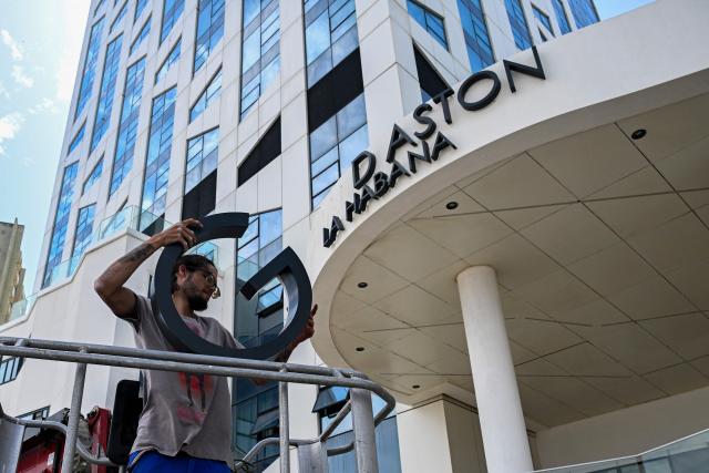 Maintenance workers remove the sign from the Hotel Grand Aston in Havana on June 5, 2026. The Asian group Archipelago International, which came to operate six hotels on the island under the Aston brand, has brought its activities in Cuba to an end. (Photo by YAMIL LAGE / AFP)