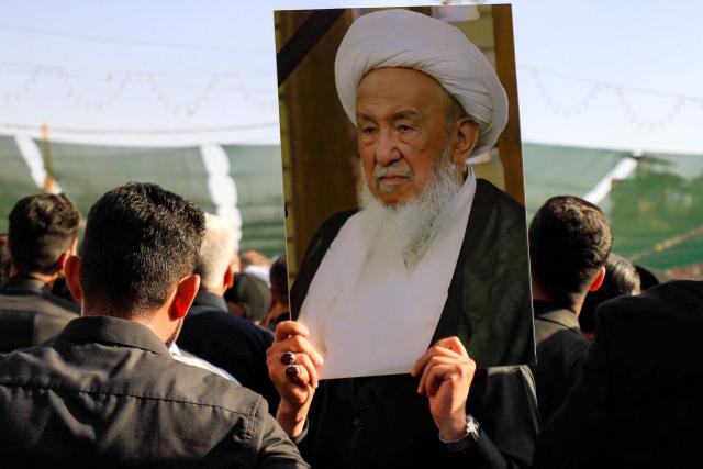 A mourner grieves with others with a picture of Iraqi Shia Muslim cleric and Grand Ayatollah Mohammad Ishaq al-Fayyad, during his funeral near the shrines of Imam Hussein and Abbas in Iraq's central holy city of Karbala on June 5, 2026. (Photo by Karrar Jabbar / AFP)
