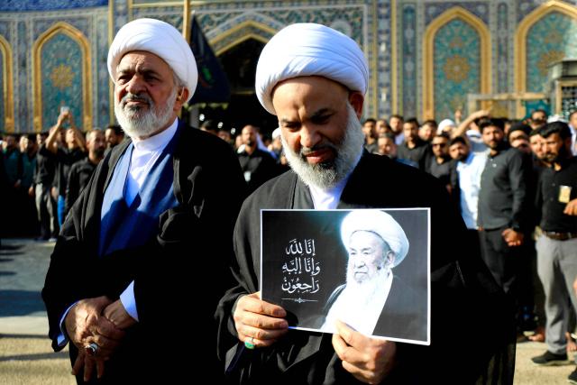 A Shia Muslim cleric grieves with others with a picture of Iraqi Grand Ayatollah Mohammad Ishaq al-Fayyad, during his funeral near the shrines of Imam Hussein and Abbas in Iraq's central holy city of Karbala on June 5, 2026. (Photo by Karrar Jabbar / AFP)