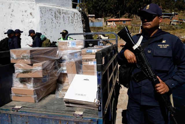 A police officer stands guard as a worker from the National Office of Electoral Processes (ONPE) loads electoral material onto a boat bound for the islands of Amantani in Lake Titicaca, in Puno, southern Peru, on June 5, 2026. Right-wing candidate Keiko Fujimori and leftist Roberto Sanchez will face off in Peru's presidential runoff on June 7, 2026. (Photo by Juan Carlos CISNEROS / AFP)