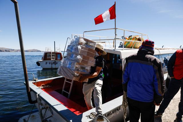 A worker from the National Office of Electoral Processes (ONPE) unloads electoral material from a boat on the island of Amantani in Lake Titicaca in Puno, southern Peru, on June 5, 2026. Right-wing candidate Keiko Fujimori and leftist Roberto Sanchez will face off in Peru's presidential runoff on June 7, 2026. (Photo by Juan Carlos CISNEROS / AFP)