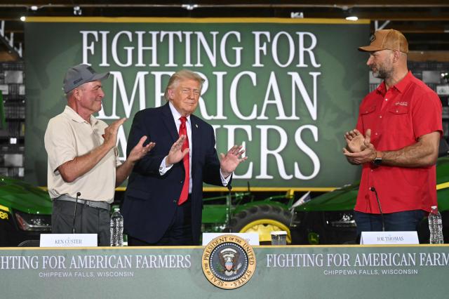 US President Donald Trump (C) is applauded by Custer Farms owner Ken Custer (L) and Hall of Fame Farms owner Joe Thomas (R) as he arrives for a roundtable on "American Agriculture" at Custer Farms in Chippewa Falls, Wisconsin, on June 5, 2026. (Photo by SAUL LOEB / AFP)
