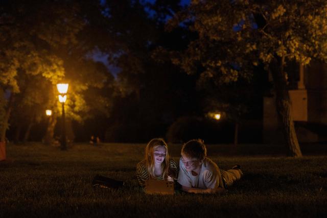 teenagers lay on the grass in the evening in Kyiv on June 5, 2026, amid the Russian invasion of Ukraine. (Photo by Tetiana DZHAFAROVA / AFP)