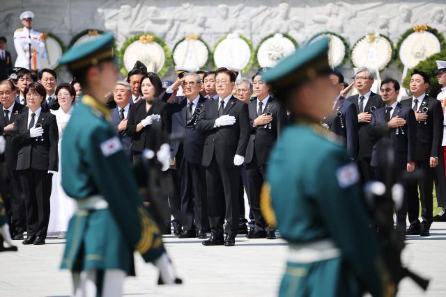 South Korea's President Lee Jae Myung and his wife Kim Hea Kyung stand for the national anthem during a ceremony marking the 71st Memorial Day to commemorate veterans and independent activists at the National Cemetery in Seoul on June 6, 2026. (Photo by KIM HONG-JI / POOL / AFP)