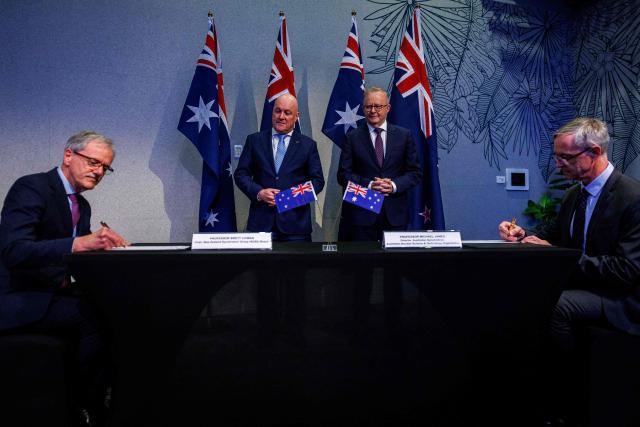 New Zealand Prime Minister Christopher Luxon (2nd-L) and Australian Prime Minister Anthony Albanese (2nd-R) watch New Zealand Synchrotron Group director Brett Cowan (L) and Australia Synchrotron Group and Nuclear Science and Technology Organisation (ANSTO) director Michael James sign a preferred access agreement following the annual Australia–New Zealand Leaders' Meeting at Noosa on June 06, 2026. (Photo by Patrick HAMILTON / AFP)
