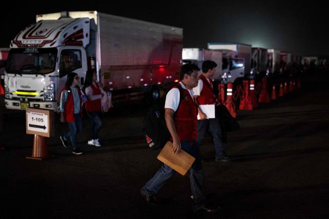 Workers of Peru's National Office of Electoral Processes (ONPE) walk next to trucks loaded with electoral material in Lima on June 5, 2026. Right-wing candidate Keiko Fujimori and leftist Roberto Sanchez will face off in Peru's presidential runoff on June 7, 2026. (Photo by ERNESTO BENAVIDES / AFP)