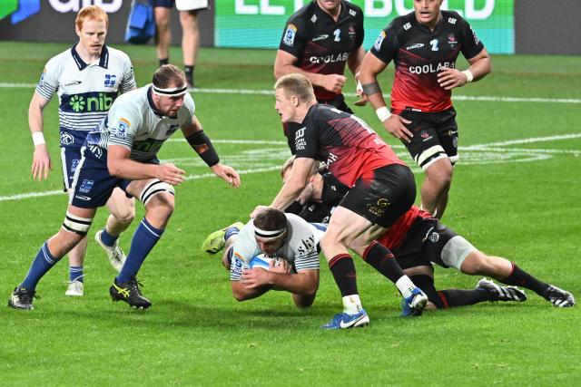 Blues' Bradley Slater (C) is tackled by Crusaders' defence during the Super Rugby Pacific quarterfinal match between the Canterbury Crusaders and Blues at One New Zealand Stadium in Christchurch on June 6, 2026. (Photo by Sanka VIDANAGAMA / AFP)