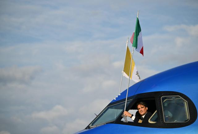 The pilot adjusts flags as Pope Leo XIV (not pictured) prepares to board his plane heading to Madrid at Rome's Fiumicino airport, on June 6, 2026. Pope Leo XIV is visiting Spain June 6-12 with stops in Madrid, Barcelona, and the Canary Islands, where he will meet with migrants and organisations dedicated to helping them. (Photo by Alberto PIZZOLI / AFP)