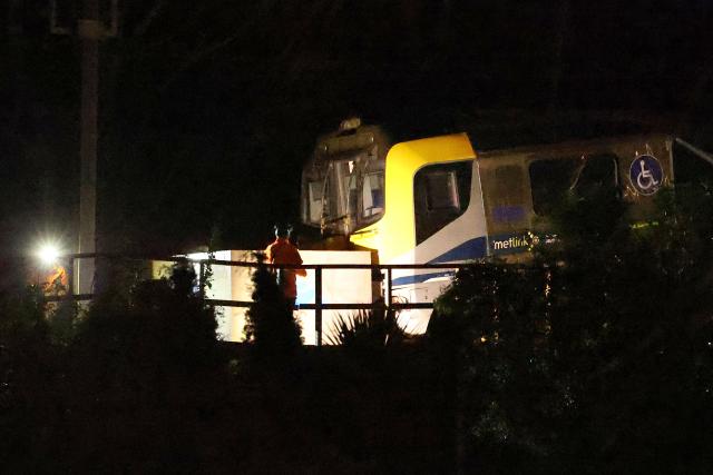 Emergency services workers inspect a train that derailed at Khandallah Station in New Zealand's capital Wellington on June 6, 2026. Around six people were injured when a train derailed in New Zealand's capital Wellington on June 6, police said. (Photo by BEN STRANG / AFP)