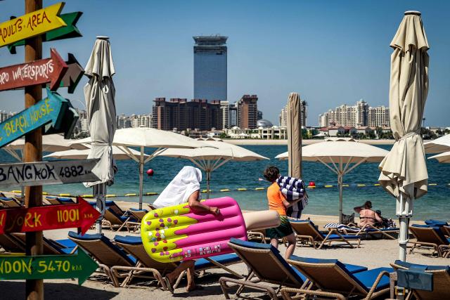 A boy walks with towels past lounge chairs along the beach at the Anantara The Palm Dubai Resort in Dubai on June 6, 2026. (Photo by FADEL SENNA / AFP)