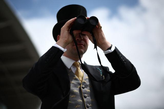 A racegoer uses a pair of binoculars ahead of racing on the second day of the Epsom Derby Festival horse racing event in Surrey, southern England on June 6, 2026. (Photo by Henry Nicholls / AFP)