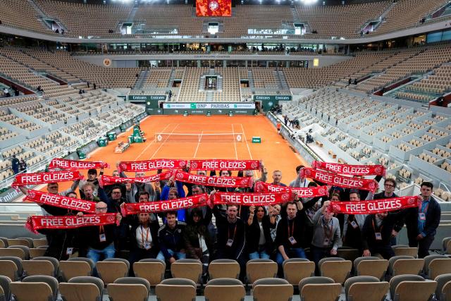 Journalists pose ahead of the women's singles final on the Court Philippe-Chatrier to call for the release of French journalist Christophe Gleizes, who is detained in Algeria since 2024, on day 14 of the French Open tennis tournament at the Roland-Garros Complex in Paris on June 6, 2026. An Algerian court cleared the way for a presidential pardon of a detained French journalist by rejecting an appeal from prosecutors for a tougher sentence and acknowledging the defendant's withdrawal of his own appeal, his lawyers said on June 3, 2026. (Photo by Christophe ENA / POOL / AFP)