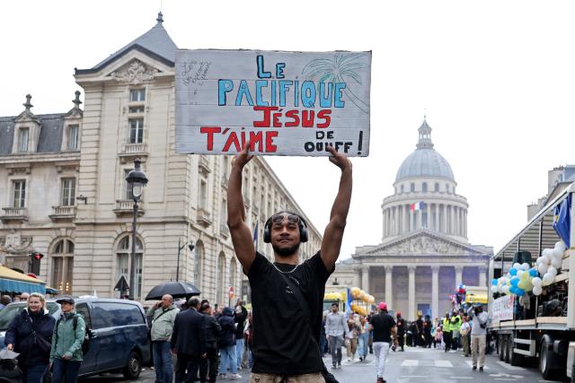 A man holds a slogan reading "The peaceful Jesus loves you like crazy" during the Marche pour Jesus (March for Jesus) Christian event, in front of the Pantheon in Paris on June 6, 2026. Tens of thousands of faithful are expected on June 6, in around fifteen French cities for the 'Marches for Jesus,' an expression of Evangelical pride that are attracting more and more young Catholics. (Photo by Xavier GALIANA / AFP)