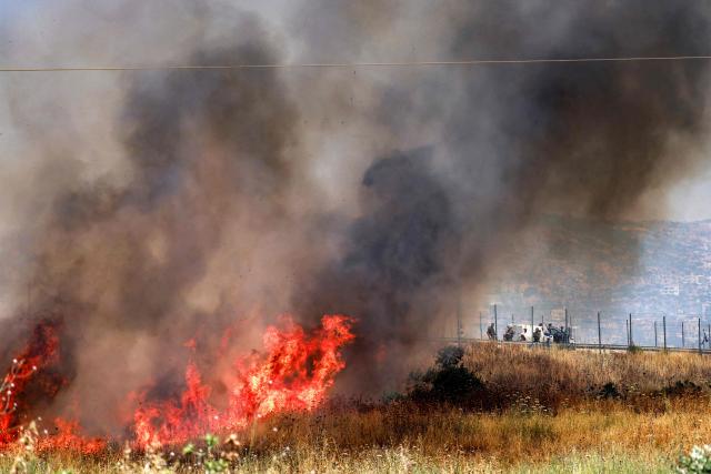 Israeli forces look on as a fire blazes in a field in the Palestinian town of Huwara in the occupied West Bank on June 6, 2026, after a reported arson attack by Israeli settlers according to local officials. Shielded by what Palestinians and rights group describe as complete impunity from the law, some Israeli settlers have harassed rural Palestinian communities, vandalising property, committing arson, sometimes killing. Excluding east Jerusalem, more than 500,000 Israelis live in the occupied West Bank in settlements that are illegal under international law, among some three million Palestinians. Israel has occupied the West Bank since 1967. (Photo by Jaafar ASHTIYEH / AFP)