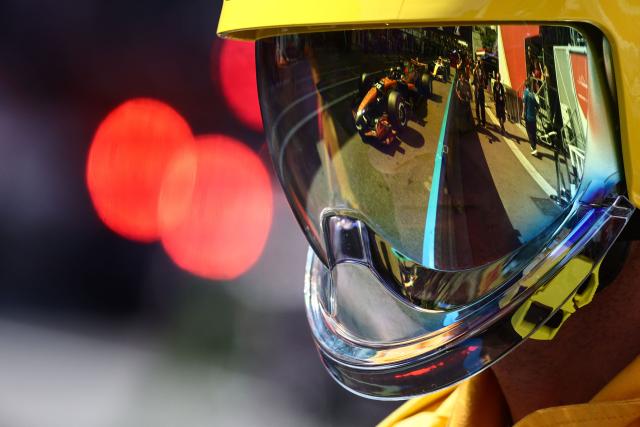 The car of McLaren's Australian driver Oscar Piastri is reflected on a firefighter's helmet visor at the start of the qualifying session at the Monaco street circuit in Monaco, ahead of the Monaco Formula 1 Grand Prix, on June 6, 2026. (Photo by Jakub Porzycki / POOL / AFP)