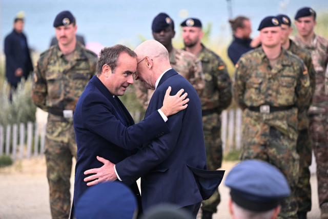 France's Prime Minister Sebastien Lecornu (L) greets Britain's Defence Secretary John Healey during an International commemorative ceremony for the 82nd anniversary of the World War II "D-Day" Normandy landings in Langrune-sur-Mer, northwestern France, of June 6, 2026. (Photo by LOU BENOIST / AFP)