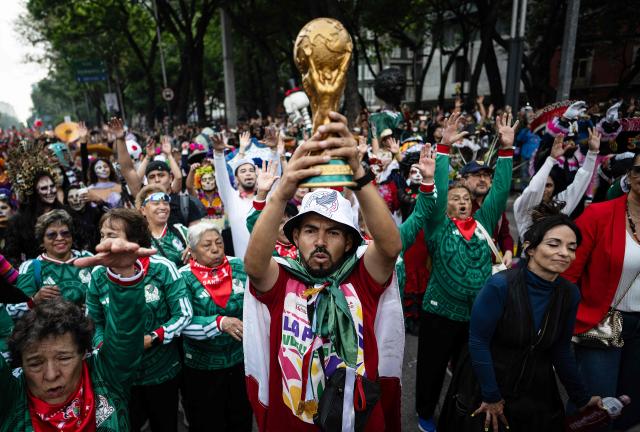 A man holds up a replica of a World Cup trophy before the start of a Guinness World Record attempt for the world’s largest Mexican Wave in Mexico City on June 6, 2026. (Photo by Carl de Souza / AFP)