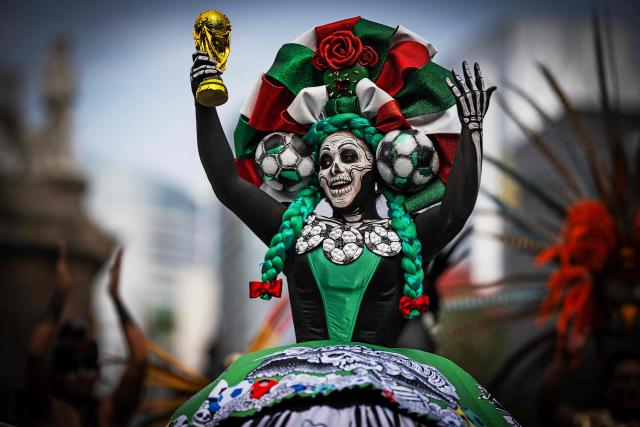 A woman dressed as a Catrina holds up a replica of a World Cup trophy before the start of a Guinness World Record attempt for the world’s largest Mexican Wave in Mexico City on June 6, 2026. (Photo by Carl de Souza / AFP)