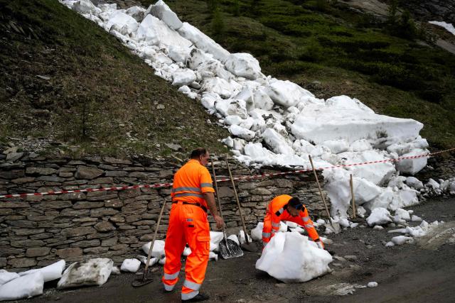 Workers remove snow from an avalanche on the road to the Colle delle Finestre during the 8th stage of the Giro d'Italia Women 2026 - Tour of Italy Women cycling race between Rivoli and Sestriere, on June 6, 2026. (Photo by MARCO BERTORELLO / AFP)