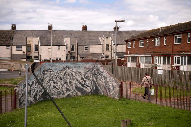 A man walks along past a playground featuring a climbing wall painted with a mural of high mountains, in Blackpool, north west England on June 6, 2026. (Photo by Oli SCARFF / AFP)