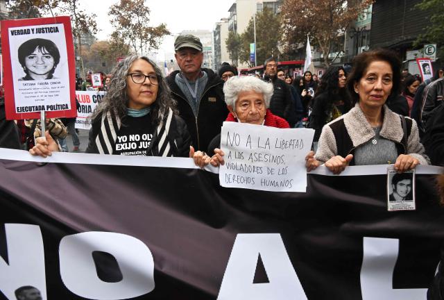 A demonstrator holds a sign reading "No to freedom for murderers who violated human rights" during a march against the human rights policies of Chile's President Jose Antonio Kast's government in Santiago on June 6, 2026. (Photo by RODRIGO ARANGUA / AFP)