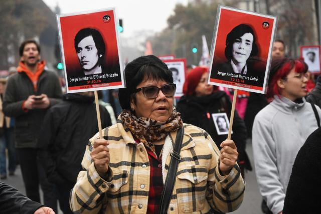 A demonstrator holds photographs of people who disappeared during Chile's dictatorship (1973-1990) during a march against the human rights policies of Chile's President Jose Antonio Kast's government in Santiago on June 6, 2026. (Photo by RODRIGO ARANGUA / AFP)