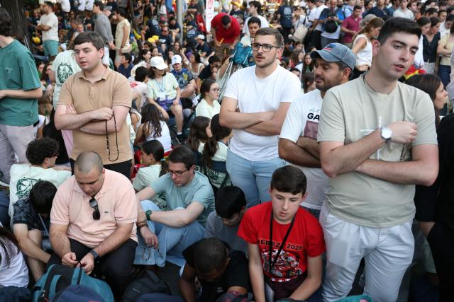 People pray the rosary as they await Pope Leo XIV's arrival to lead a prayer vigil with young people in the Plaza de Lima in Madrid on June 6, 2026. Pope Leo XIV is visiting Spain June 6-12 with stops in Madrid, Barcelona, and the Canary Islands, where he will meet with migrants and organisations dedicated to helping them. (Photo by Pierre-Philippe MARCOU / AFP)